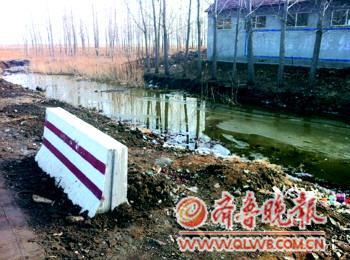 14日下午,在高密市姜庄镇李仙路段,一辆接送幼儿园孩子的面包车翻入水沟。图为出事现场已经放上了隔离墩。