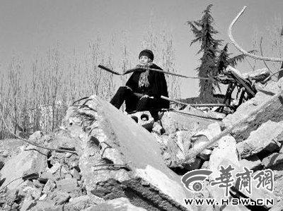 老刘80岁的老母亲坐在房屋的废墟上