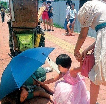 女童为清洁工撑伞照片